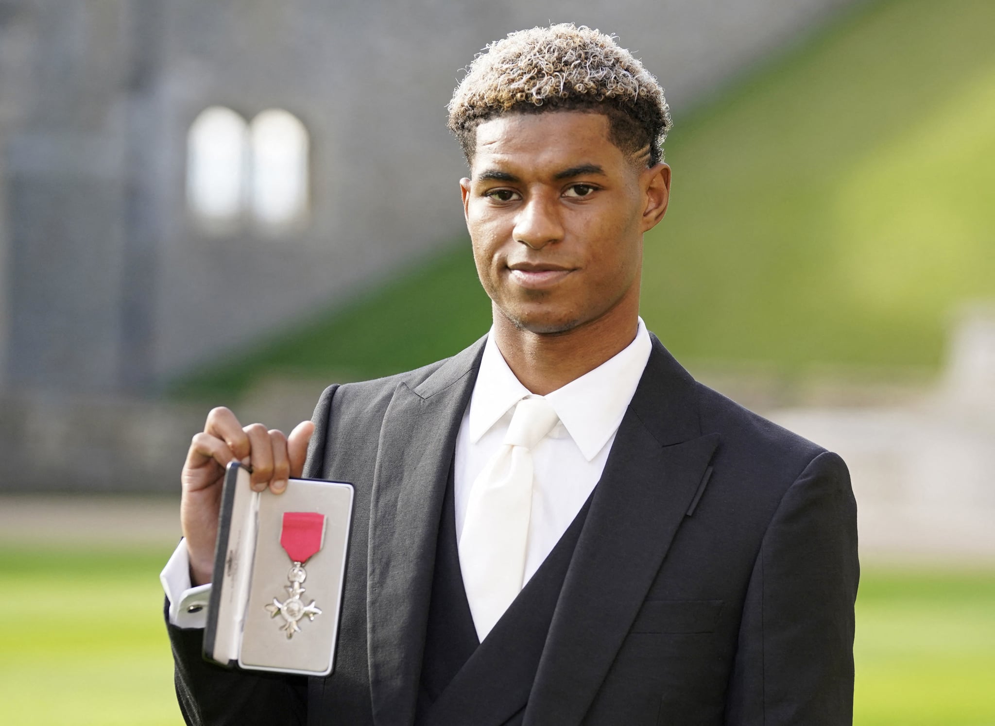 Manchester United and England footballer Marcus Rashford poses with his medal after being appointed a Member of the Order of the British Empire (MBE) for services to Vulnerable Children in the UK during the Covid-19 pandemic, following an investiture ceremony at Windsor Castle in Windsor, west of London on November 9, 2021. (Photo by Andrew Matthews / POOL / AFP) (Photo by ANDREW MATTHEWS/POOL/AFP via Getty Images)