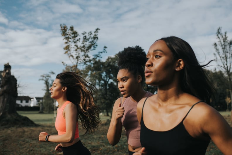 Women breathe while running through a sunny park at sunrise.