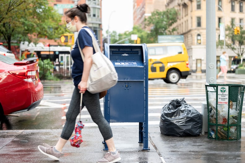 NEW YORK, NEW YORK - AUGUST 25: A woman wearing a mask walks past a USPS mailbox as the city continues Phase 4 of re-opening following restrictions imposed to slow the spread of coronavirus on August 25, 2020 in New York City. The fourth phase allows outd