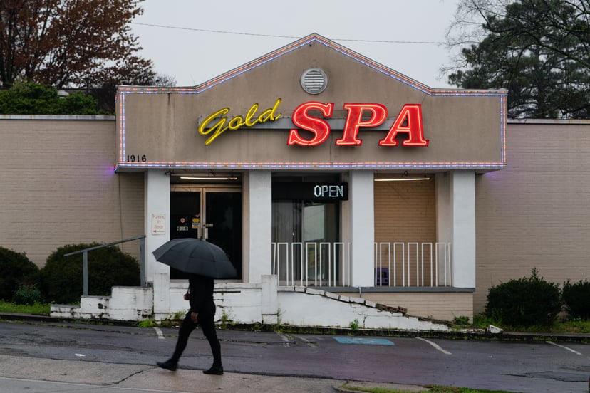 ATLANTA, GA - MARCH 17: A man walks past a massage parlor where three women were shot and killed on March 17, 2021 in Atlanta, Georgia. Suspect Robert Aaron Long, 21, was arrested after a series of shootings at three Atlanta-area spas left eight people de