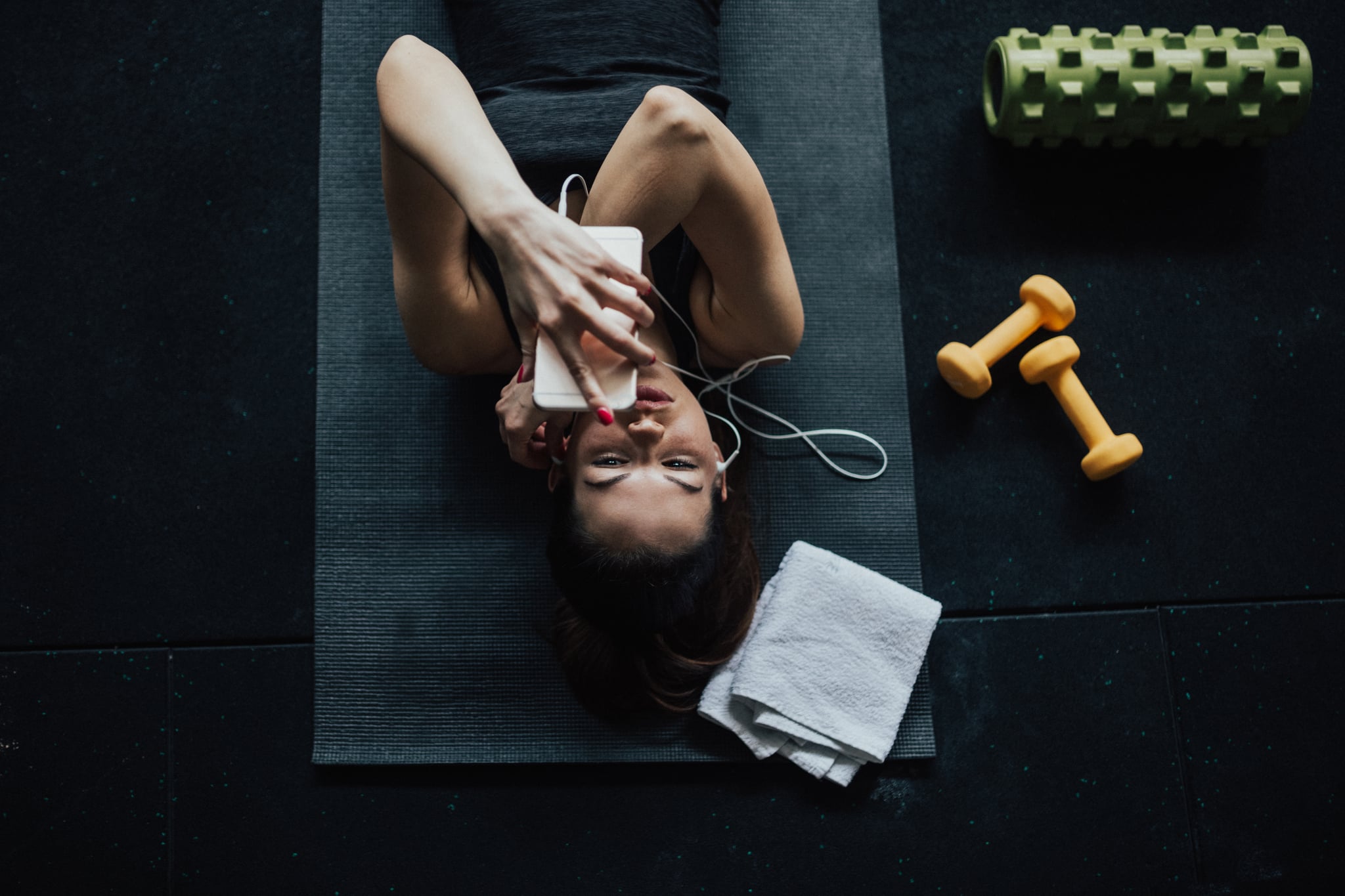 Woman listening to music and relaxing on the gym floor