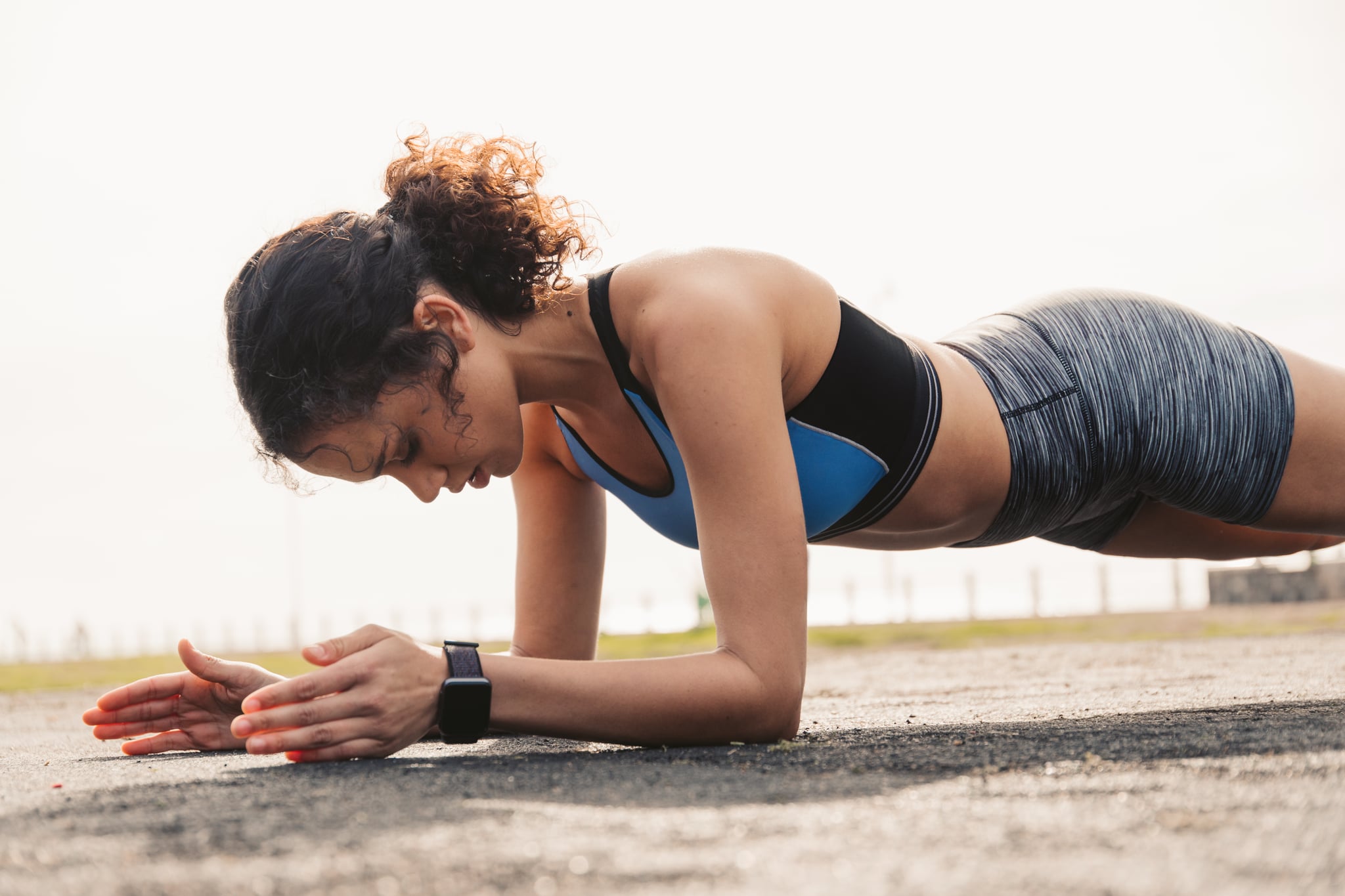 Sporty woman doing plank exercise at park.