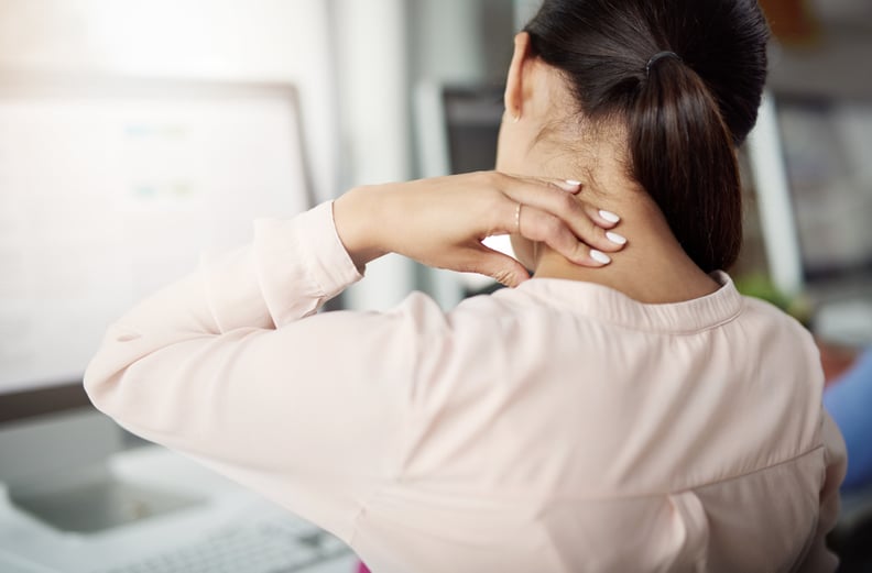 Rearview shot of a young businesswoman experiencing neck pain while working at her desk in a modern office