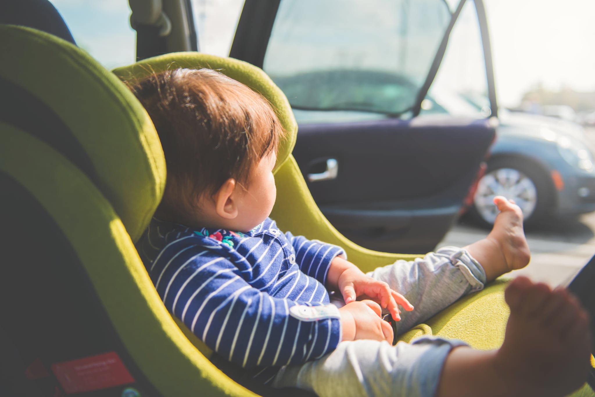 A baby girl 8 months old sitting in her car seat enjoying the warmth of the sun.