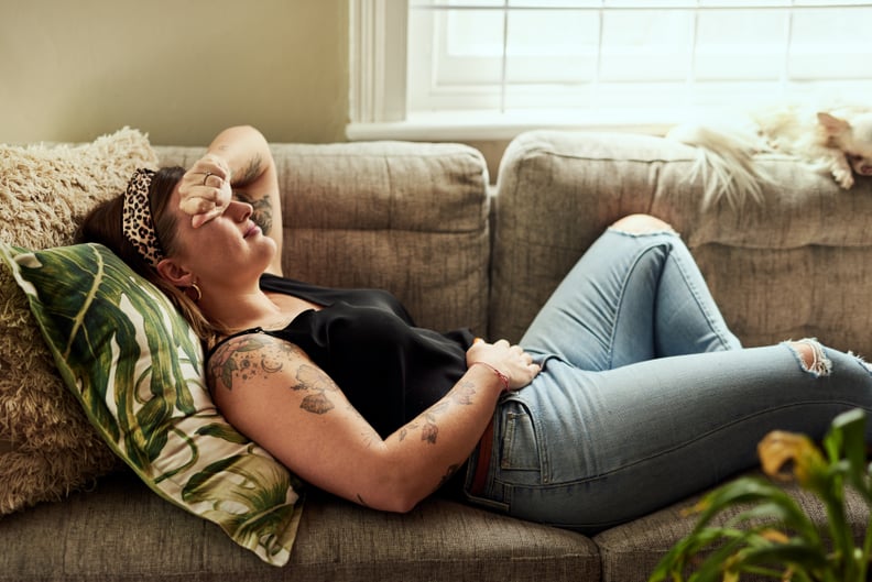 Shot of a young woman suffering from stomach cramps on the sofa at home