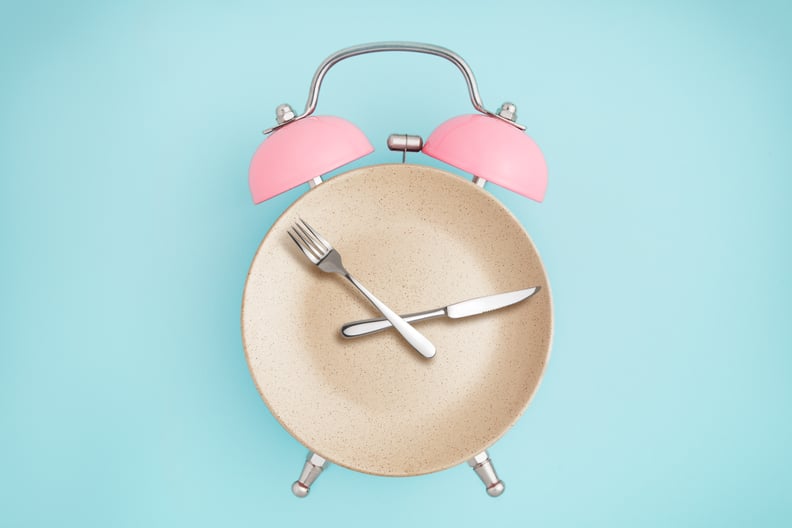 Alarm clock and plate with cutlery . Concept of intermittent fasting, lunchtime, diet and weight loss 5:2