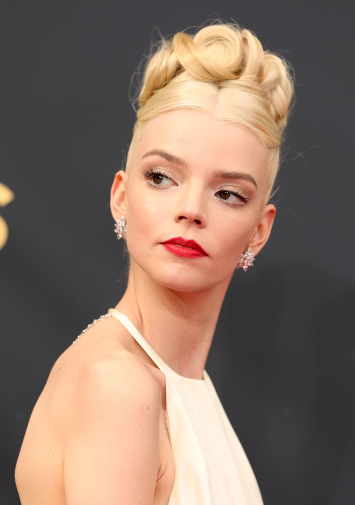When you come of age in the spotlight, award shows are kind of like prom. Anya Taylor-Joy demonstrated as much with her beauty look at the 2021 Emmy Awards. The actress, whose leading role in The Queen's Gambit earned her a nomination, wore her hair in an updo you don't see as often these days, yet an updo that was a staple of high school dances in the early 2000s. 
Beautifully executed by Gregory Russell, the hairstyle consisted of a high bun with curled strands swirling around it. Her makeup, by Georgie Eisdell, was kept pretty simple apart from a classic red lip. The entire beauty look nicely complemented Taylor-Joy's backless Dior gown.

    Related:

            
            
                                    
                            

            ICYMI, Binge-Watch the Emmys Red Carpet Right Here
