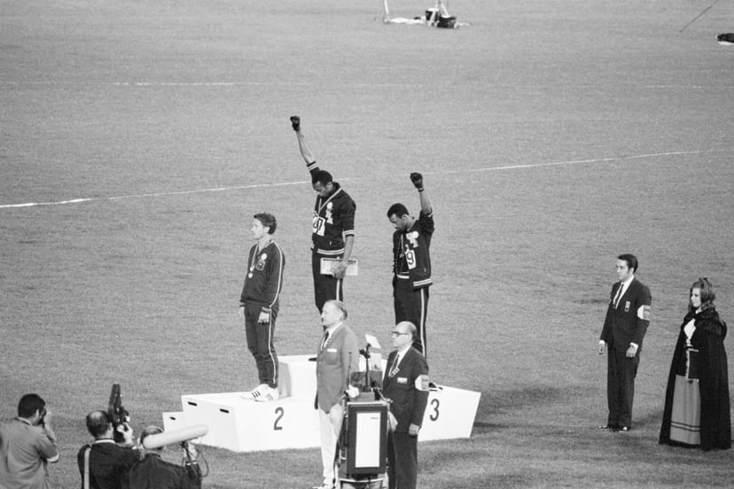 Tommie Smith and John Carlos, gold and bronze medalists in the 200-meter run at the 1968 Olympic Games, engage in a victory stand protest against unfair treatment of blacks in the United States. With heads lowered and black-gloved fists raised in the blac