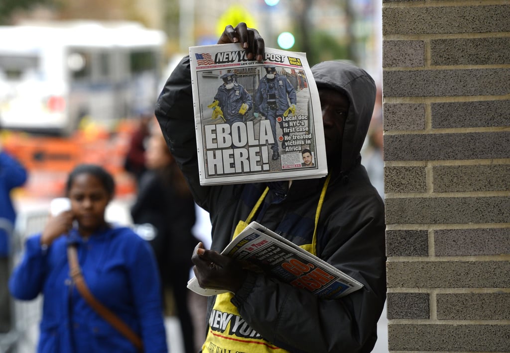 A man in NYC held up a newspaper that announced the first case of Ebola in the city.