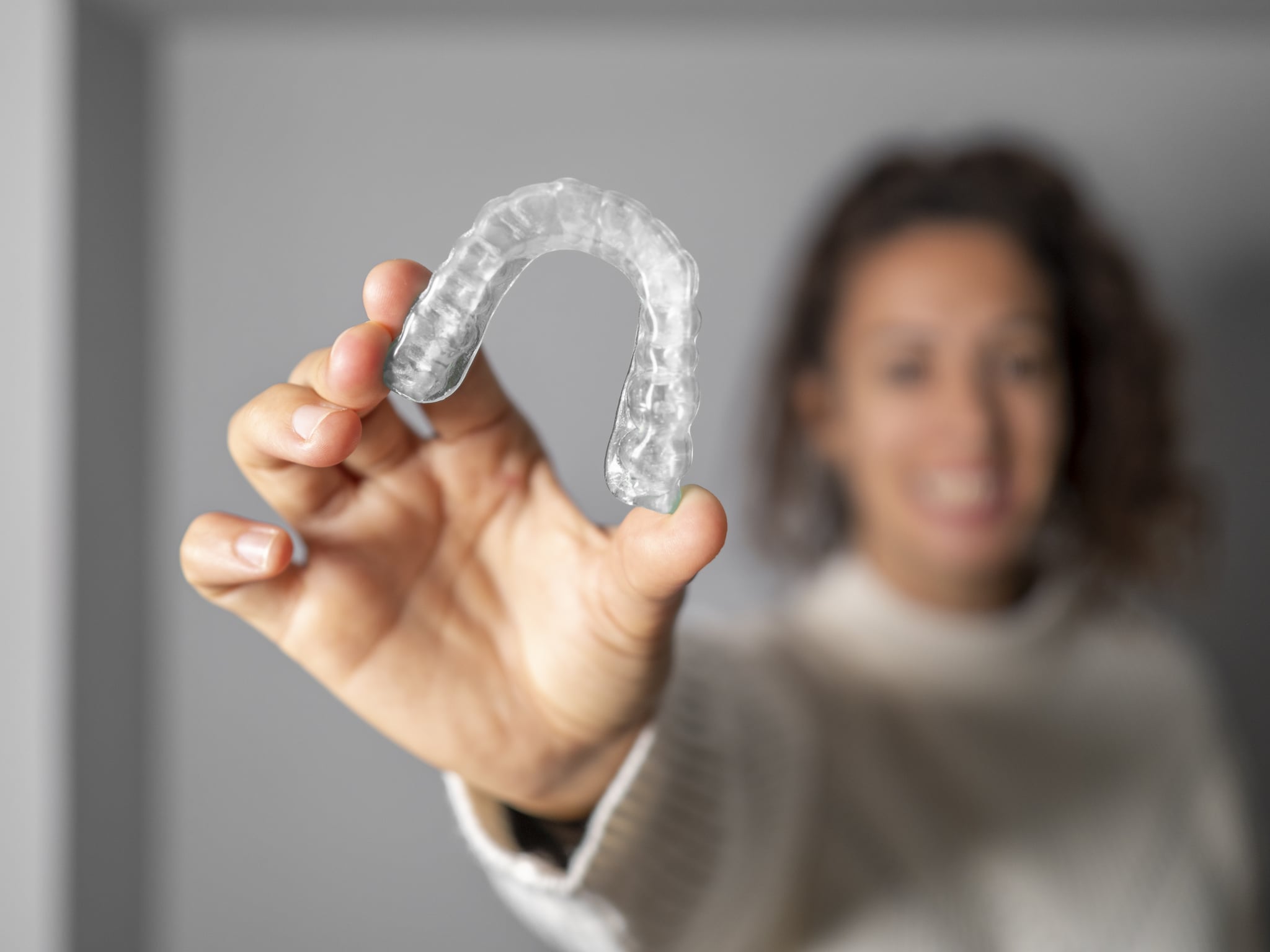 Young woman holding an invisible, transparent translucent orthodontics. Focus on orthodontics.