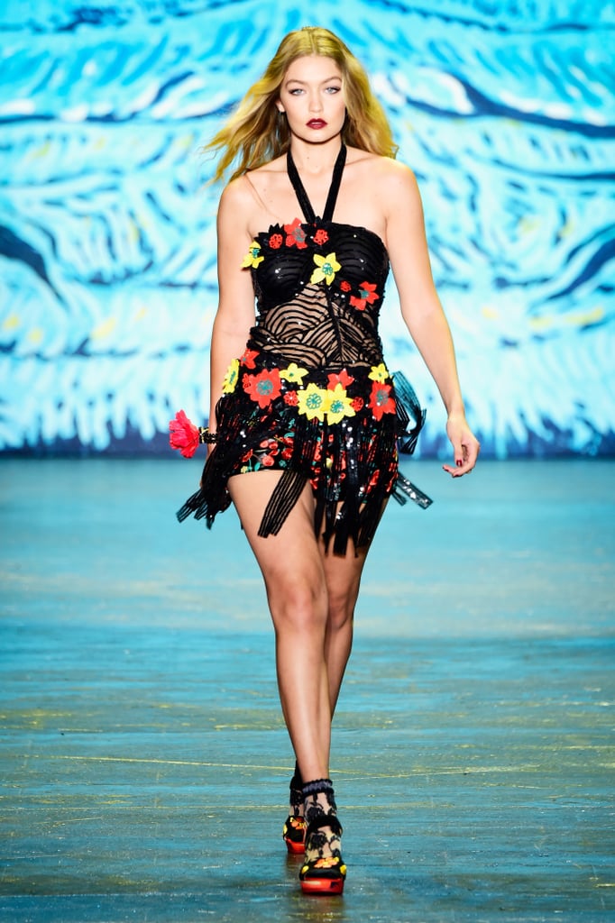 Gigi's first Anna Sui look was so sexy. Her sequined halter neck featured a fringe hemline which extended beyond her rose-embroidered leather minishorts. Gigi walked the runway in complementing red and yellow platforms that she played up with lacy ankle socks.