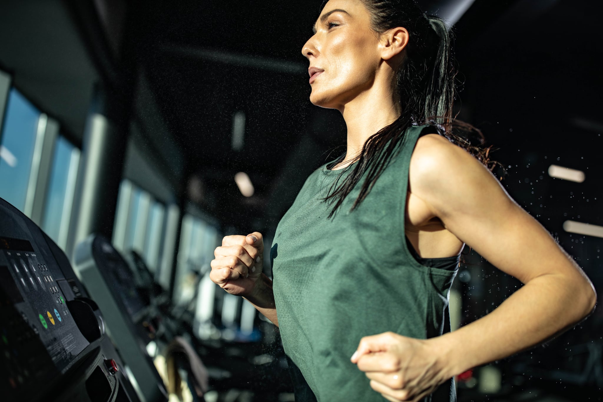 Young female athlete doing sprint interval training on a treadmill in a gym.