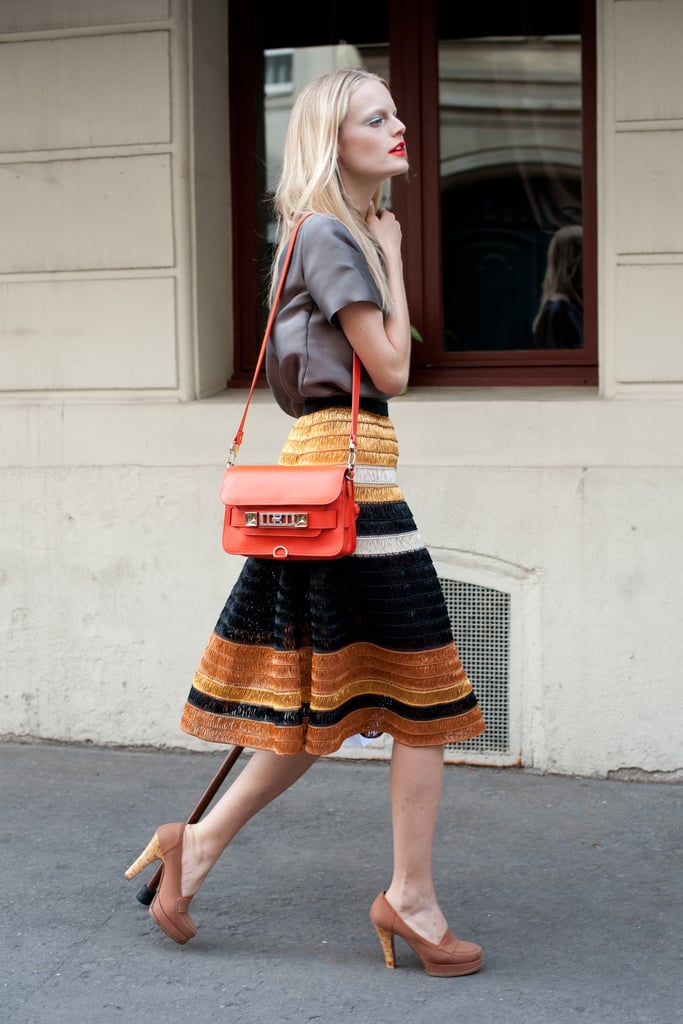 Not overly complicated, but the textural intrigue on her striped a-line skirt and a pop of cherry-red on her bag, takes this look from casual to covetable.