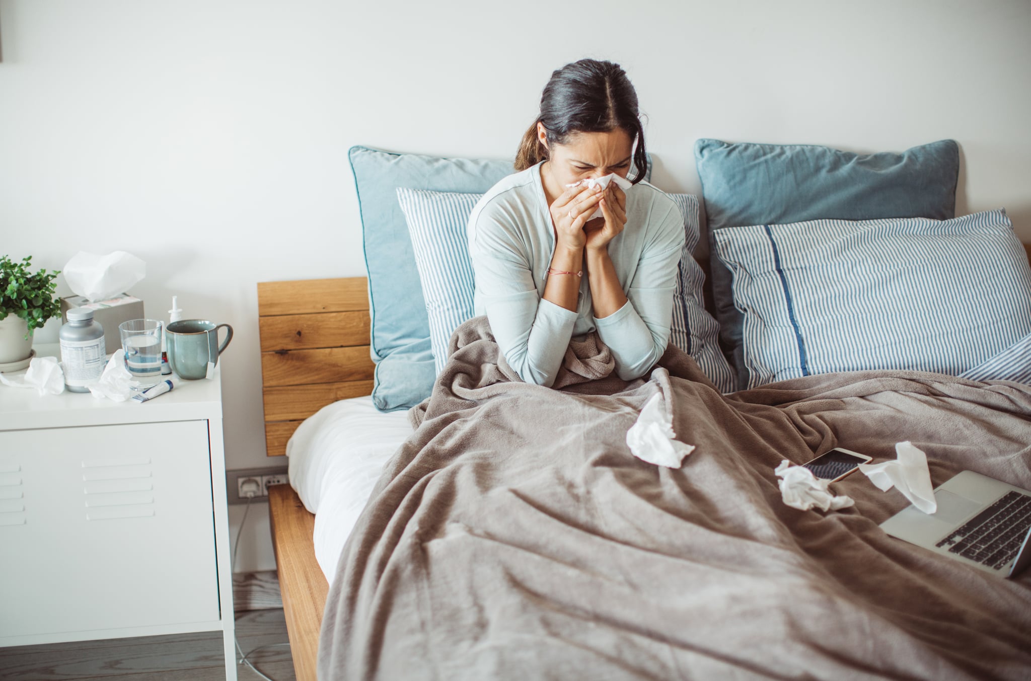 Woman sitting up in bed and blowing her nose to clear congestion on one side