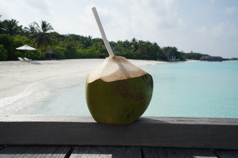 新鲜椰子沙滩上用一根吸管:椰水对你有好处吗?
