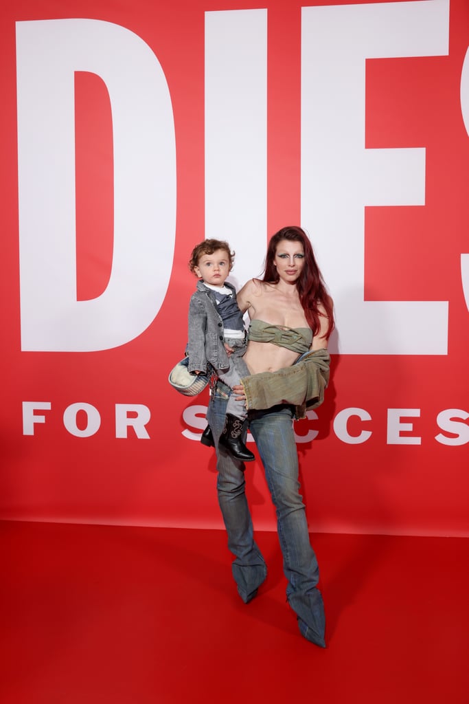 Like mother, like son. On Feb. 22, Julia Fox attended the Diesel fall/winter 2023 presentation during Milan Fashion Week with her 2-year-old son Valentino. The two stepped out in matching denim looks, with Fox in a pair of extremely low-rise jeans that were actually pantaboots. She wore a denim jacket draped off her shoulders and a strapless bandeau top. Fox held Valentino on the red carpet, showing off his double-denim outfit as well as his cute cowboy boots.
This was Valentino's very first fashion week appearance — not to mention his first-ever fashion show — and with a parent like Fox, good style is in his jeans. Fox, who shares her son with ex-husband Peter Artemiev, announced Valentino's birth on Valentine's Day in 2021. "My forever valentine, Valentino. Born on January 17th, 2021. The best day of my life," she wrote on Instagram. Now that Valentino is a little older, the mother-son duo can take on the red carpet together, looking like a high-fashion duo.
In the past, Fox has stressed the importance of "maximum transparency," which extends to some areas of her personal life, including parenting. To this point, she's given a highly relatable tour of her apartment, spoken about raising her child in New York City, and opened up about her experience with postpartum depression. Now, she's letting fans in on another (albeit more fashionable) milestone. Read on to see photos of Fox and Valentino at his very first fashion show. 
Related:
Paris Hilton Reveals Her Son&apos;s Name and Explains Its Significance: "Means So Much"