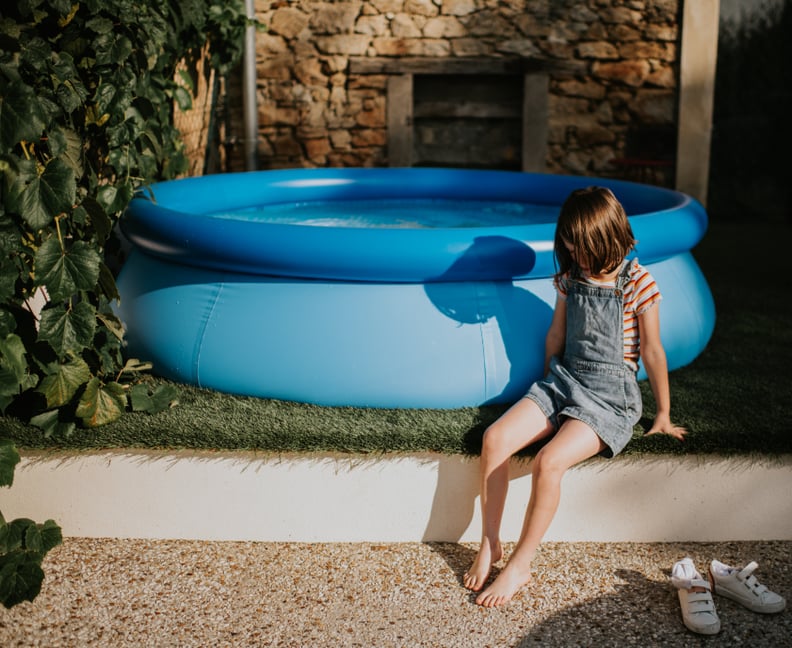 Child looking bored sitting next to an inflatable pool