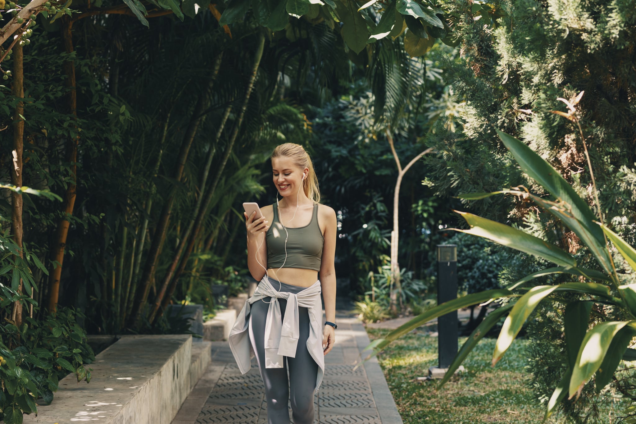 Woman uses her smartphone to listen to music while working out outdoors.