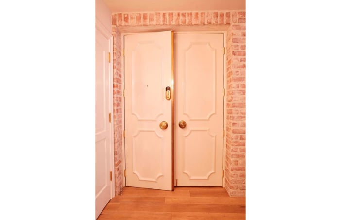 A stylish pair of doors welcome guests into the condo, located in a 1970s Brutalist-style apartment building.