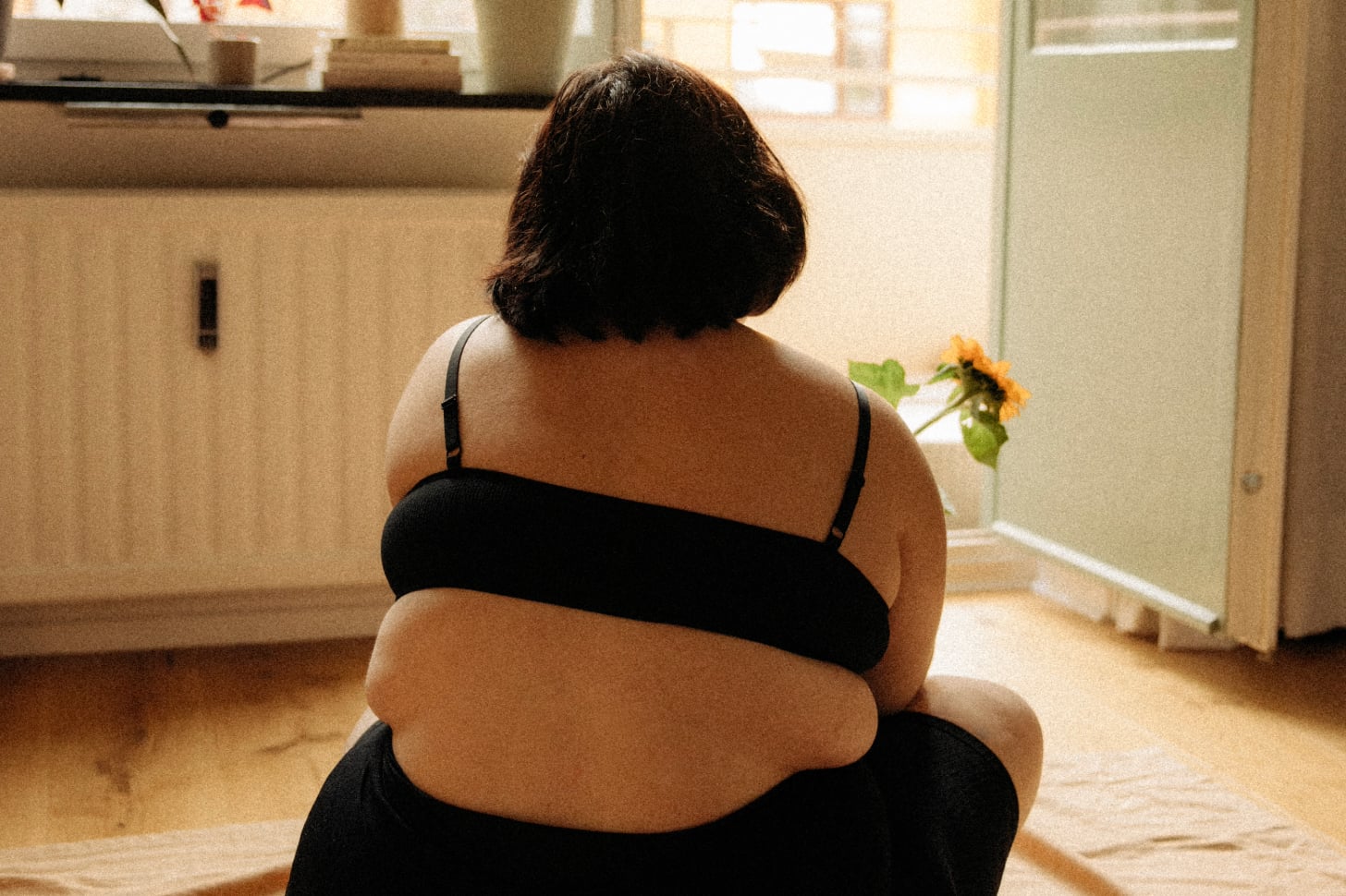 Woman sitting on ground in black underwear.