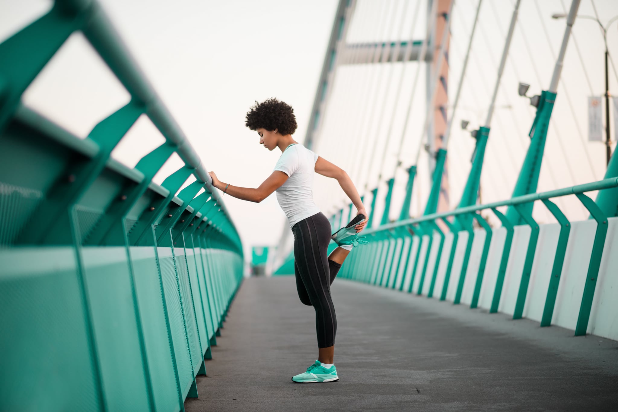 Healthy young slim fitness girl warming up on bridge