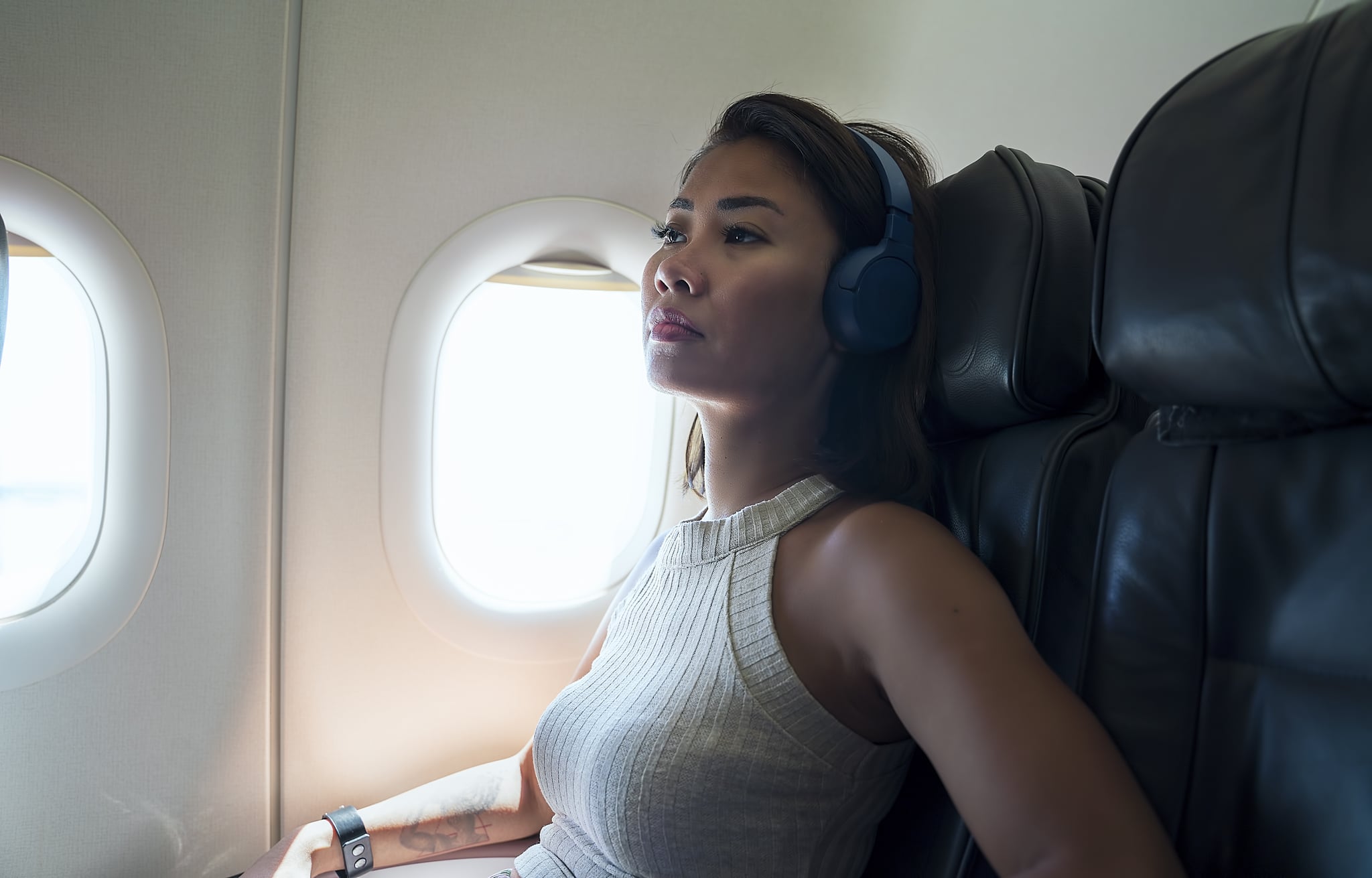A fearful woman sitting in the window seat of the plane looking worried. A fearful woman sitting in the window seat of the plane looking worried.