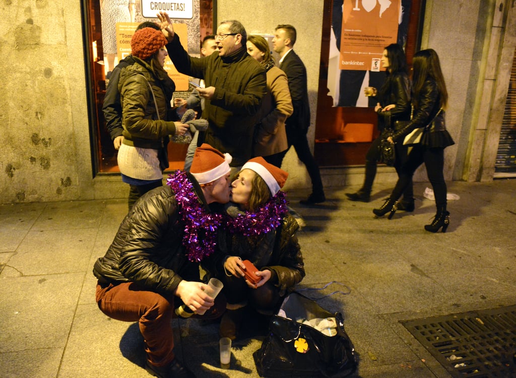 A curbed couple donning Santa hats got kissy in Madrid, Spain.