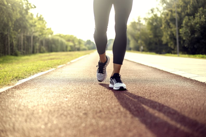 Unrecognizable muscular man running or walking on track field, low angle view of his running shoes.