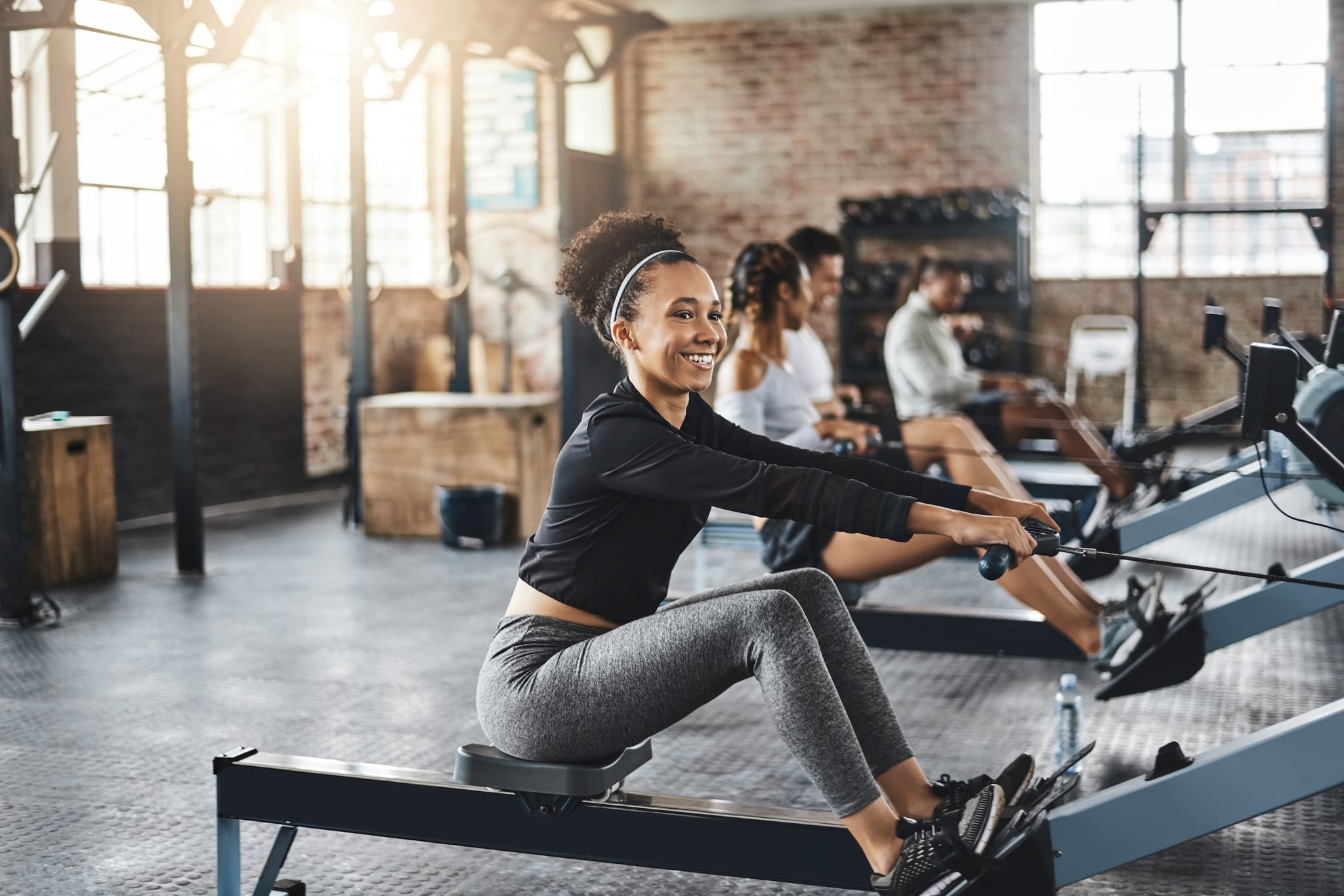 Shot of a young woman working out with a rowing machine in the gym