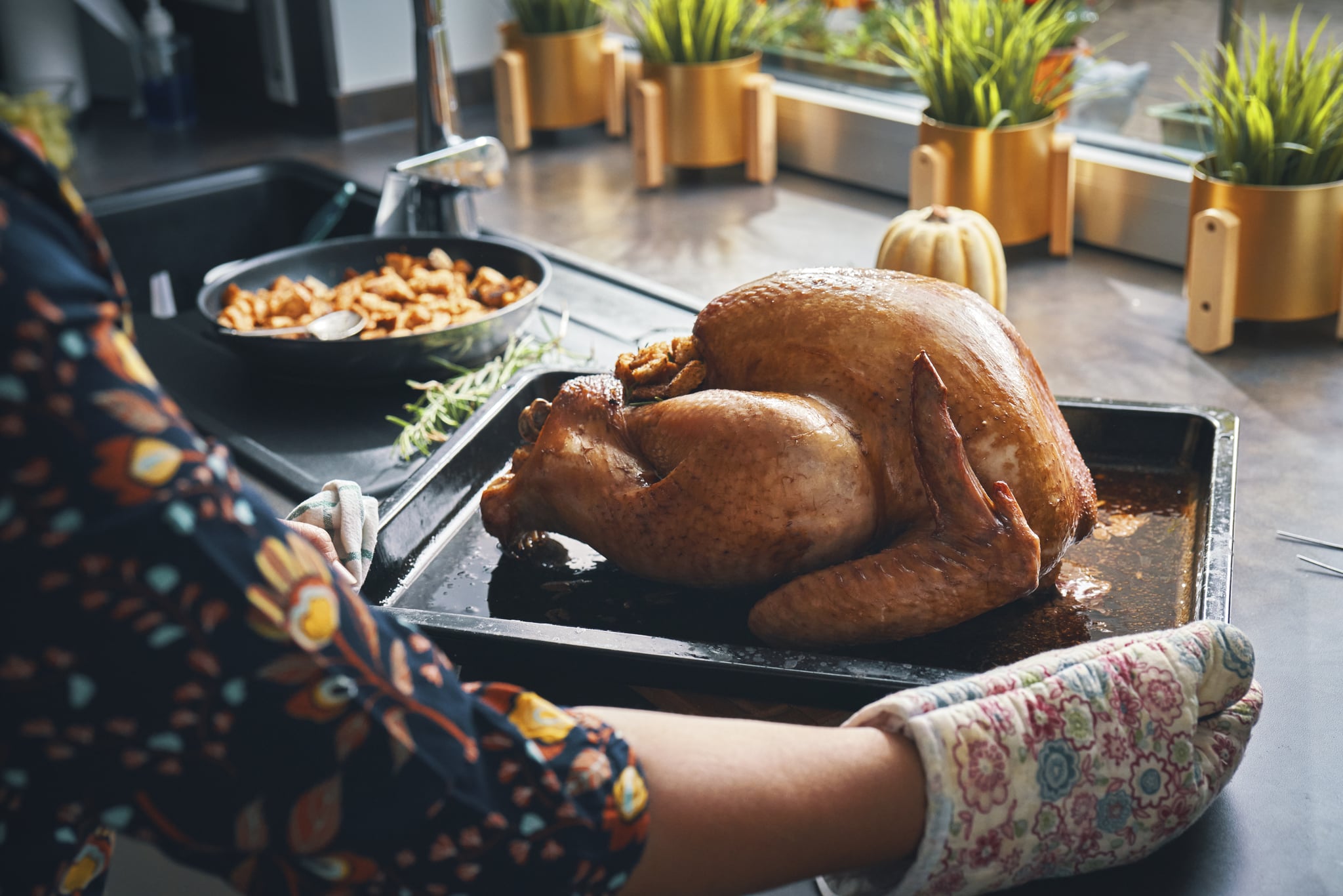 A woman's arms preparing a Thanksgiving meal with crispy turkey skin and a whole roast turkey on a platter.