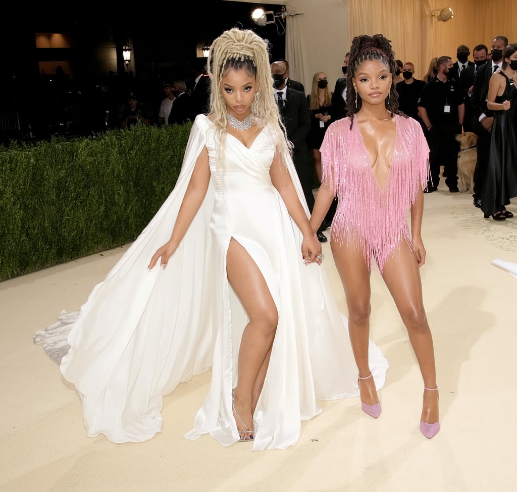 Sisters who sing together also style together, and Chloe and Halle are crystal-covered proof that some looks are even better in pairs. While attending their first Met Gala on Monday, the sisters supported another set of siblings — Kate and Laura Mulleavy — by wearing complementary Rodarte outfits with V necklines and figure-hugging bodices. Inspired by classic Hollywood sirens like Marilyn Monroe and Grace Kelly, Chloe — who wowed us with her "Have Mercy" performance at the MTV VMAs on Sunday — wore a flowing white gown with a thigh-high slit and a cape so dramatic it belongs on the back of a wedding gown. 
In contrast, Halle's sheer look was inspired by Tina Turner's love for sparkling bodysuits on stage and was decked out in glittering pink fringe from every angle. The sisters also tied their looks together even further by accessorising with Irene Neuwirth jewellery and matching high ponytails. Distinct yet spectacularly coordinated, Chloe and Halle's looks are as beautifully balanced as their voices. See their Met Gala outfits from all angles here.

    Related:

            
            
                                    
                            

            Yara Shahidi Exudes Elegance in a Met Gala Look Inspired by Josephine Baker