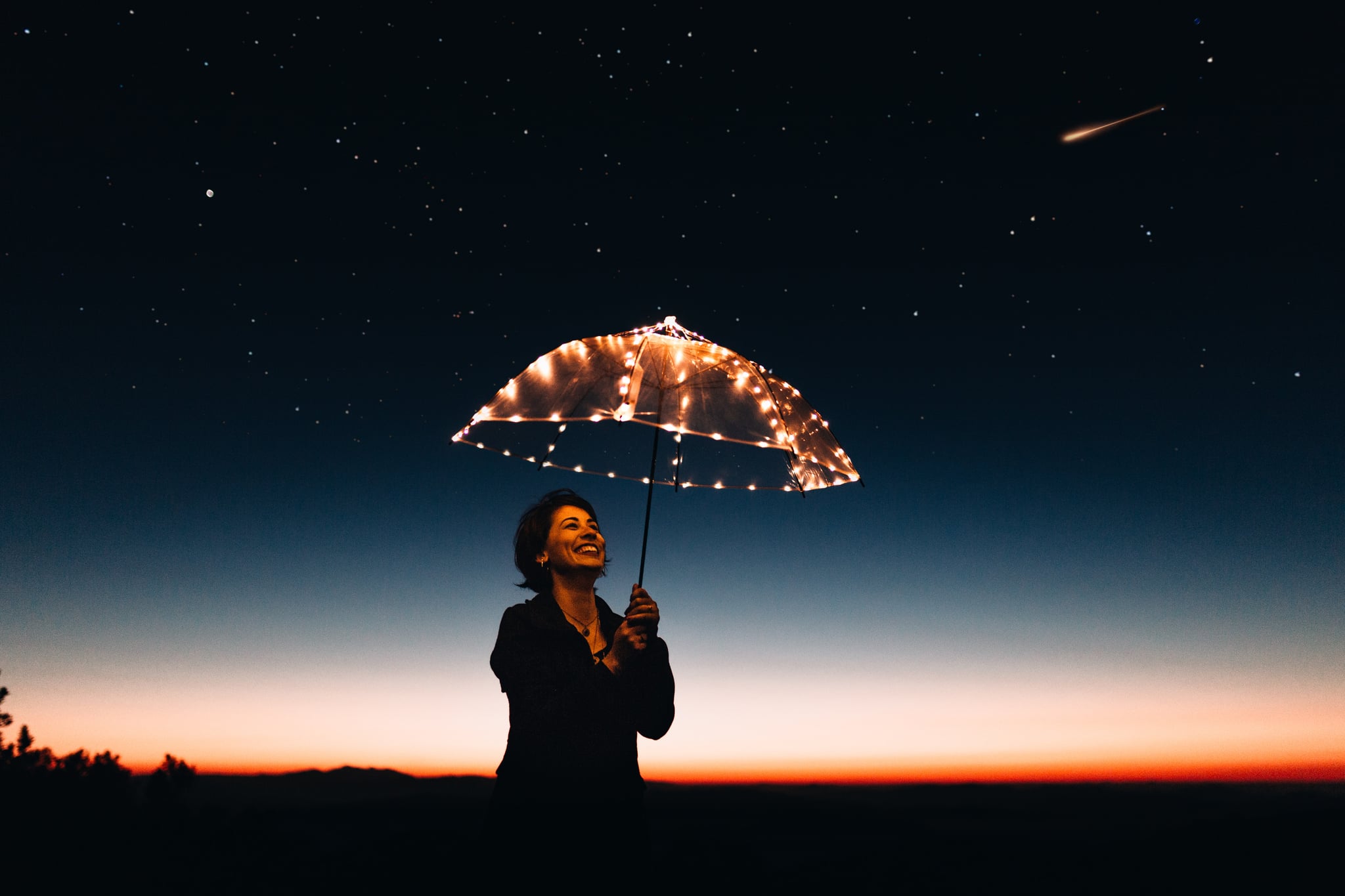 woman under night sky with lit umbrella to signify her lucky Jupiter return