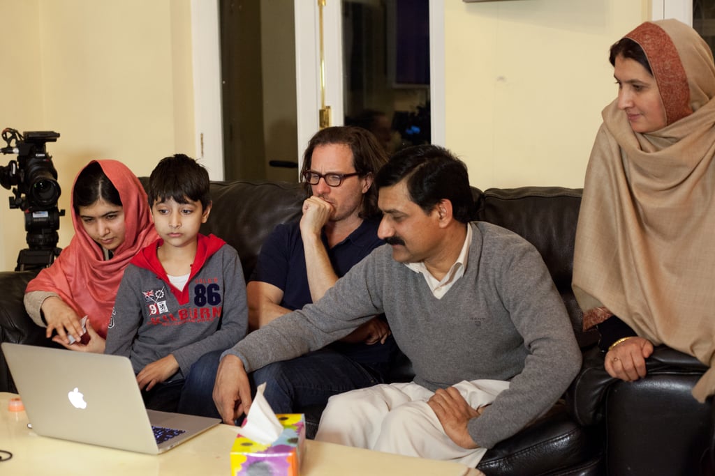 Malala watches documentary footage on the couch with her little brother Atal, the director, Zia, and her mother, Toor Pekai.