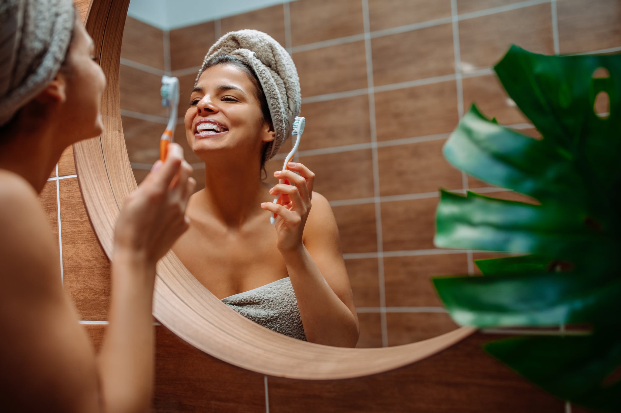 A woman brushing her teeth after a shower.