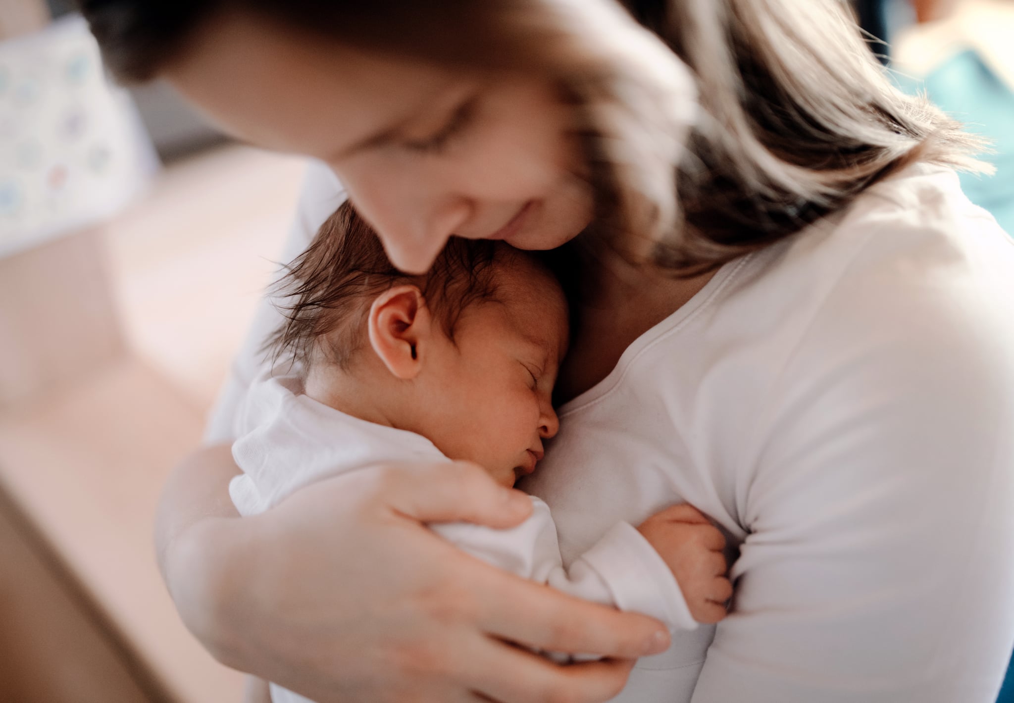 A young woman cuddling her new baby boy or girl with love.