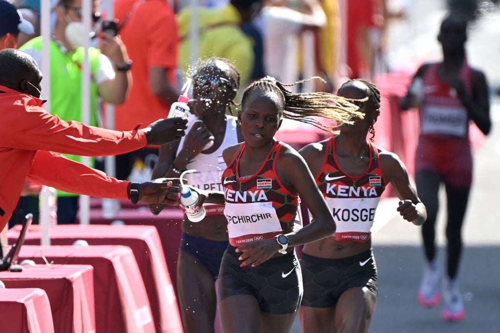 Peres Jepchirchir and Brigid Kosgei of Kenya and Lonah Chemtai Salpeter of Israel take water during the women's marathon at the 2021 Olympics.