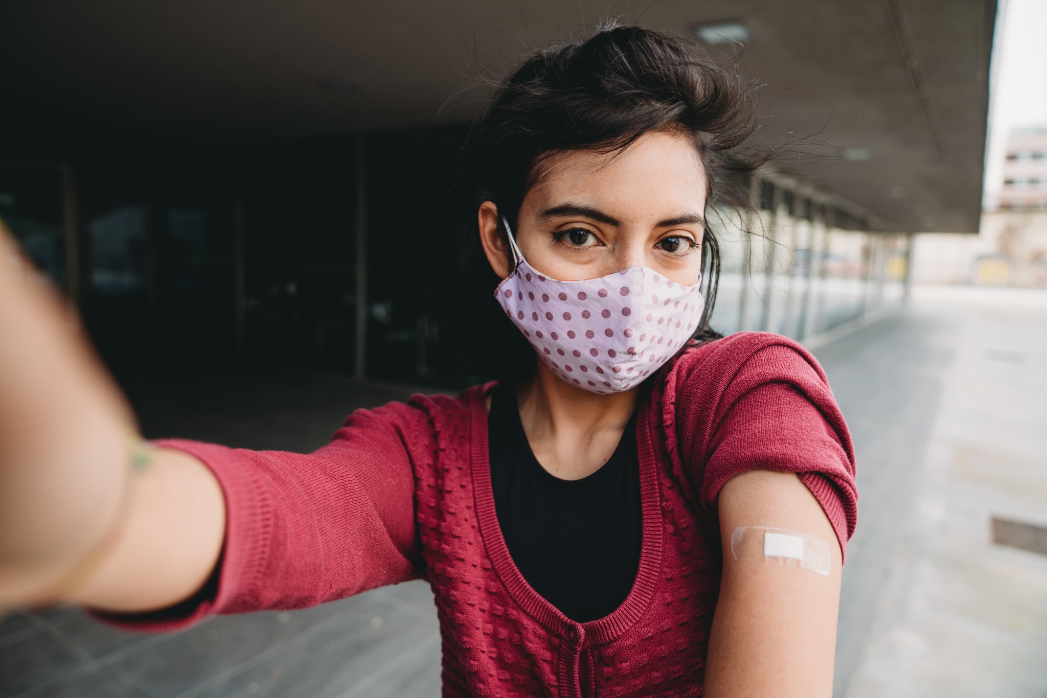 Millennial mixed race woman taking a selfie after her Covid-19 vaccination.