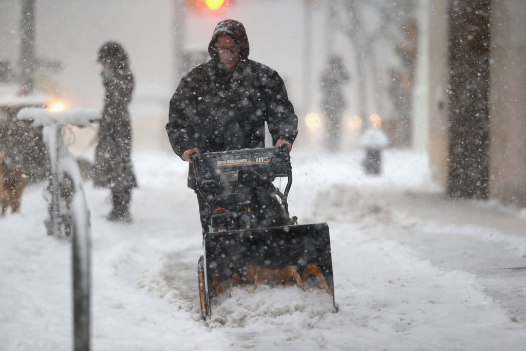 A doorman removed snow from the slushy NYC sidewalk.