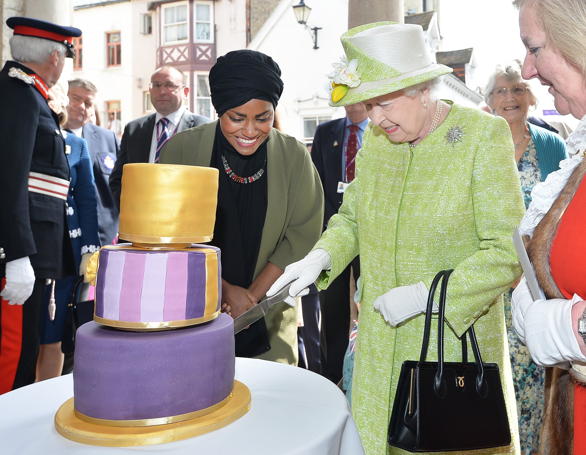 英国，温莎——4月21日:2016年4月21日，英国女王伊丽莎白二世在她90岁生日的时候，从英国烘焙大赛冠军Nadiya Hussain手中接过生日蛋糕。今天是英国女王伊丽莎白二世90岁生日。女王和爱丁堡公爵将在温莎执行公务。(图片来源:John Stillwell - WPA Pool/Getty Images)