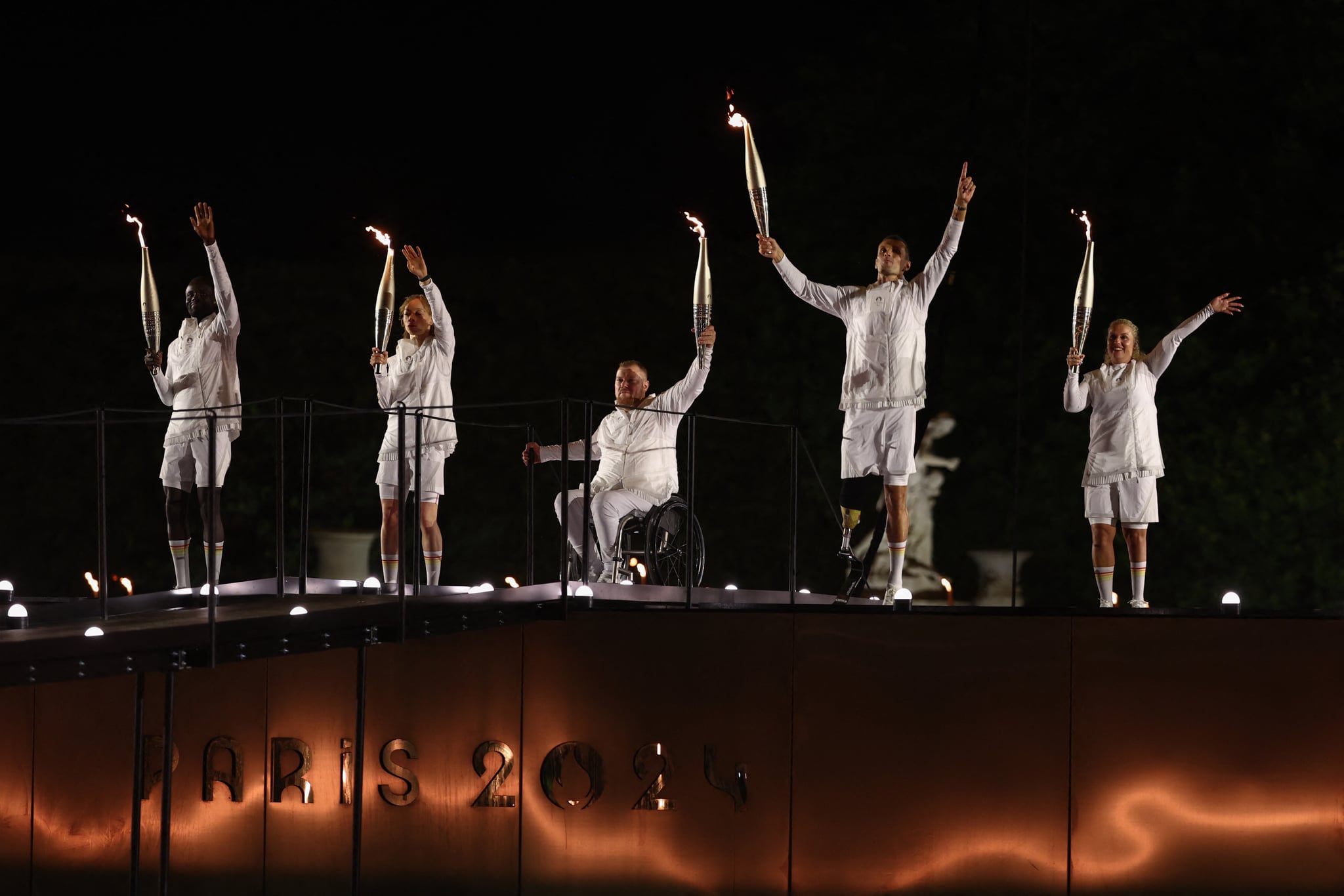 LtoR, France's paralympic torchbearers, Charles-Antoine Kaoukou, Nantenin Keita, Fabien Lamirault, Alexis Hanquinquant and Elodie Lorandi wave as they hold the flame as the Paris 2024 Paralympic Games cauldron, with the Olympic flame lit, lifts off while atached to a balloon during the Paris 2024 Paralympic Games Opening Ceremony at the Jardin des Tuileries (Tuileries Garden) in Paris on August 28, 2024. (Photo by Franck FIFE / AFP) (Photo by FRANCK FIFE/AFP via Getty Images)