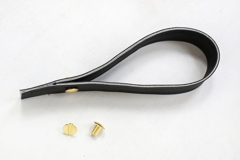 Fold the strap in half and glue the two ends together to make a loop. If you want to add some sort of decorative hardware here (like a Chicago screw or stud), just punch a hole and install the screw at the beginning where the strap goes from two layers of fabric to four.