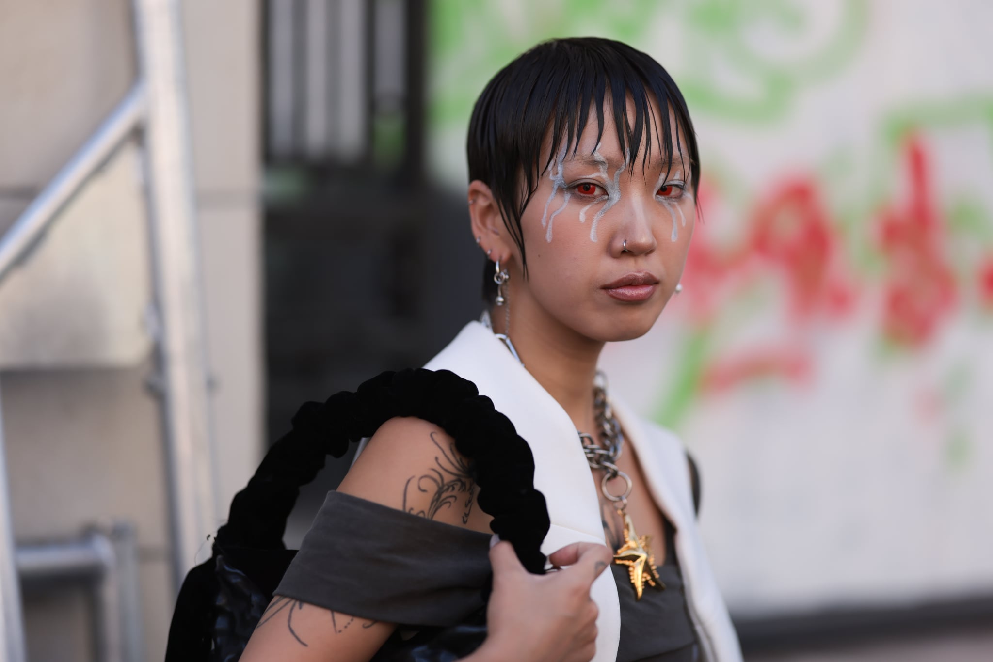 PARIS, FRANCE - OCTOBER 01: Fashion Week guest is seen wearing a black bag and a white and brown top, lots of jewellery and blue paintings on her face-skin before the Ottolinger Fashion Show during the Womenswear Spring/Summer 2024 as part of  Paris Fashion Week on October 01, 2023 in Paris, France. (Photo by Jeremy Moeller/Getty Images)