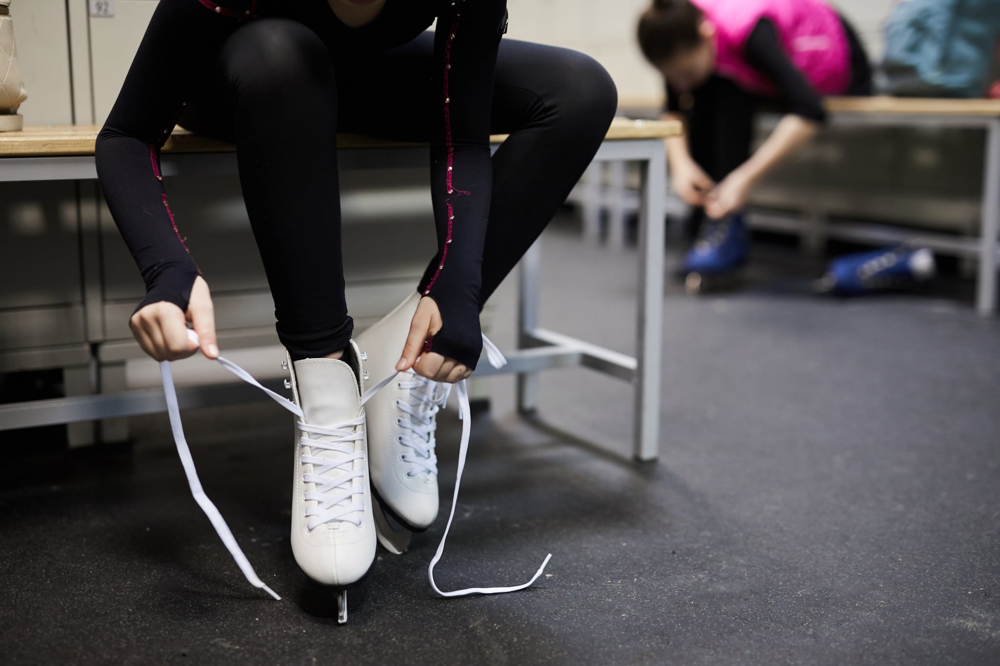 Portrait of unrecognisable girl tying skating shoe in dressing room before practice, copy space