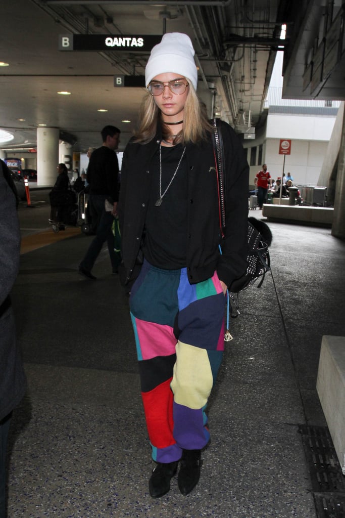 Cara Delevingne stayed warm and comfortable in a knit beanie and rainbow-colored pants.