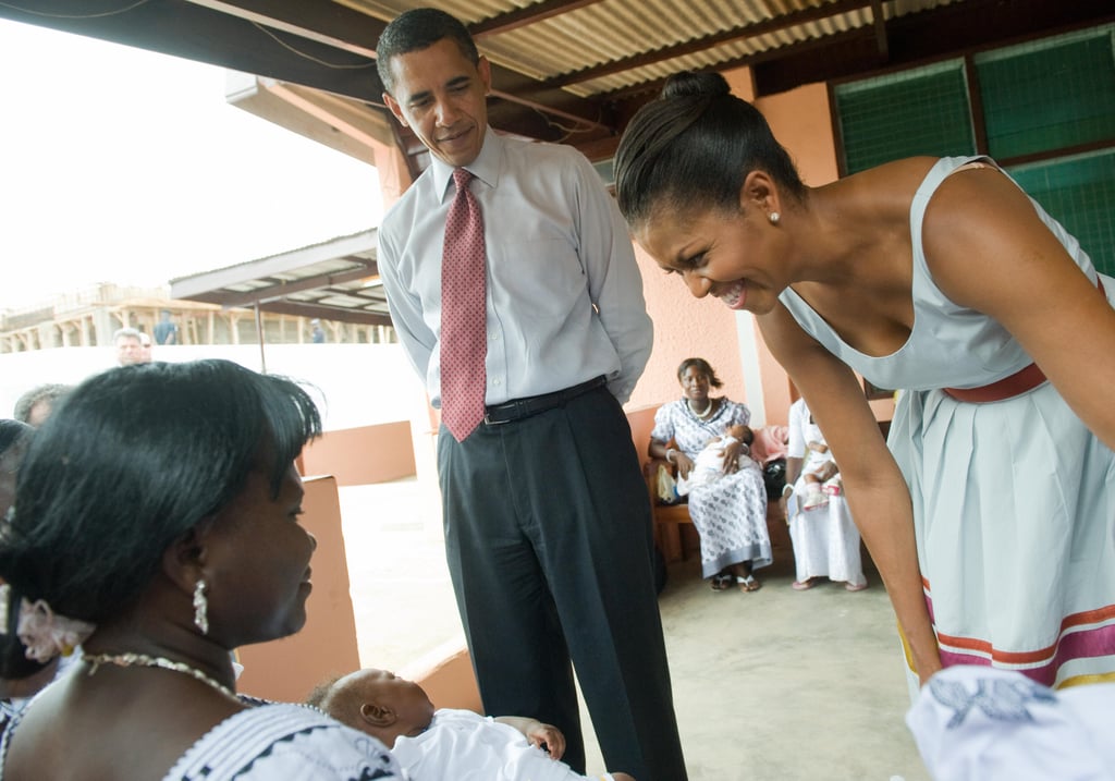 First Lady Michelle Obama smiled at a baby during a July 2009 hospital visit in Ghana.