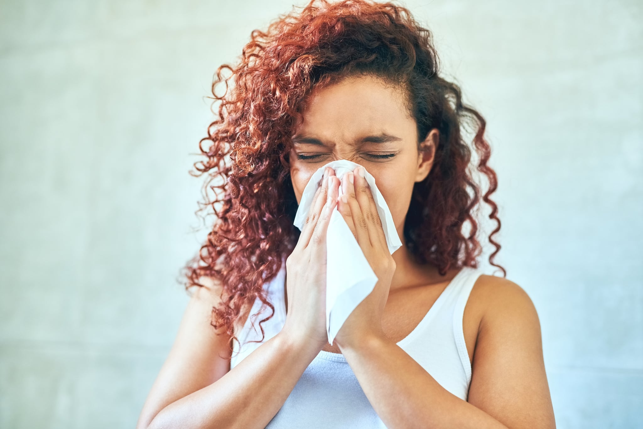 Cropped shot of a young woman blowing her nose