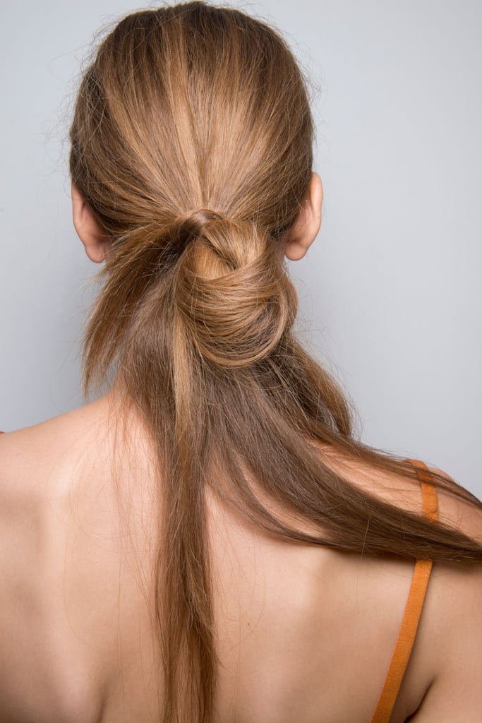 For an undone look like this one spotted backstage at the Josie Natori runway show, pull hair into a low ponytail, fold half of it up towards the base, and wrap a small section of hair around the loose ends. Then, secure with a bobby pin for extra hold.