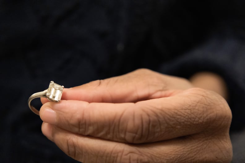A woman holds a wedding ring in her fingers, contemplating whether she should delay marriage while she has so much outstanding debt.