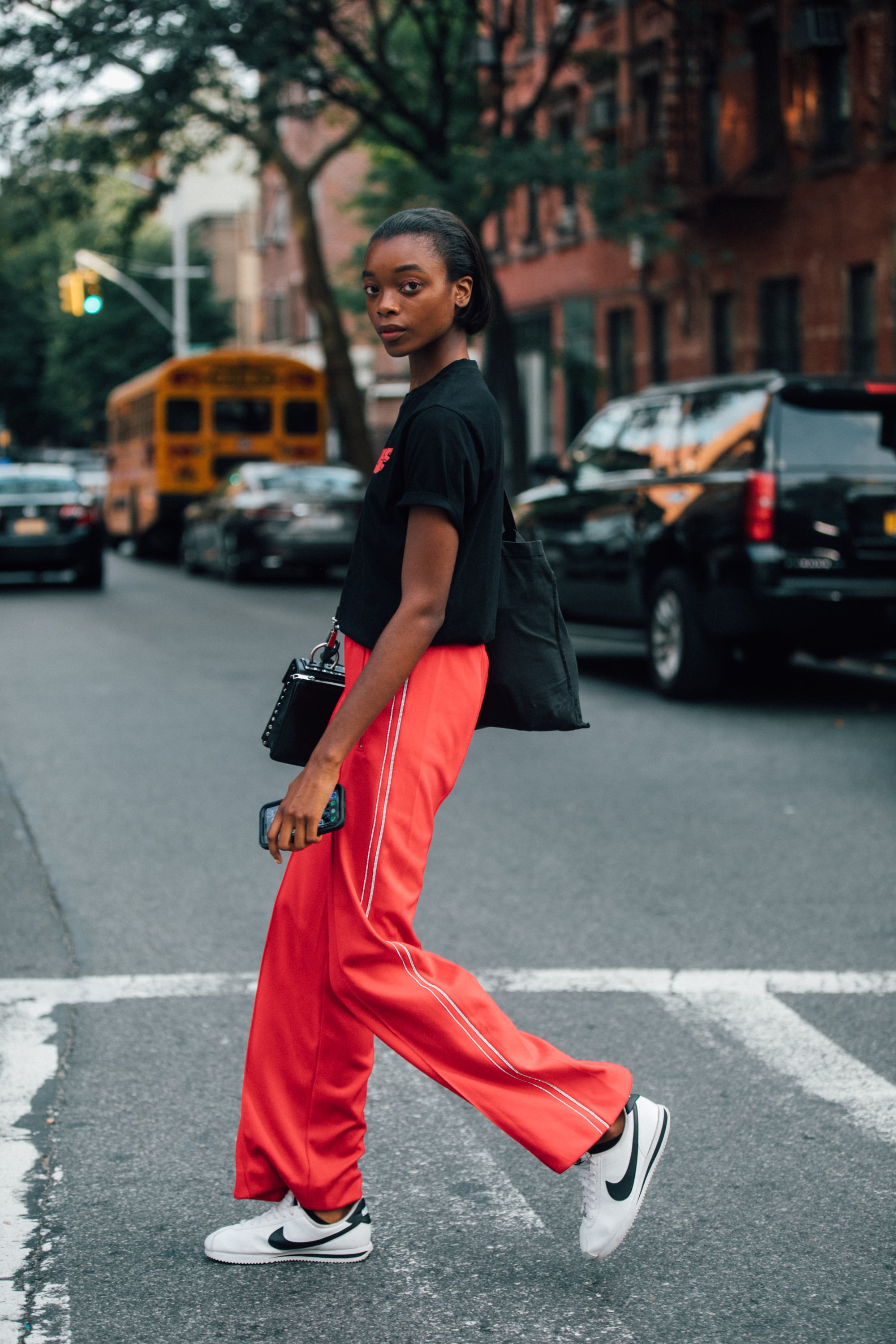 NEW YORK, NY - SEPTEMBER 6: Model Olivia Anakwe wears a black t-shirt, red pants, and white Nike sneakers during New York Fashion Week Spring/Summer 2019 on September 06, 2018 in New York City.