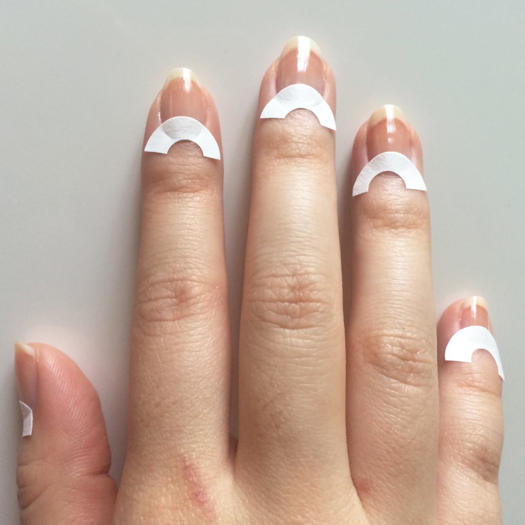 After applying your base coat, let it dry for a few minutes. Next, cut paper reinforcements in half (or you can just use whole ones) and place them at the base of your nails. This will create the half-moon shape of your manicure.